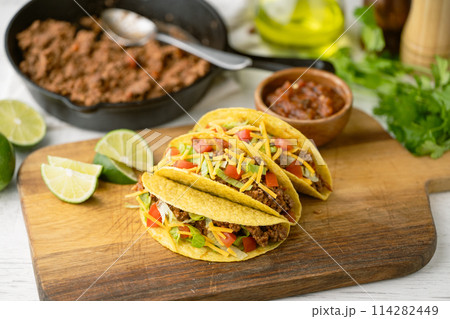yellow hard shell tacos  on cutting board 114282449