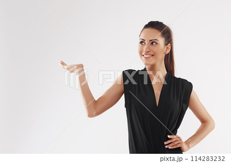 Woman smiles surprise showing product .Beautiful girl pointing to the side . Presenting your advertisement. Expressive facial expressions 114283232