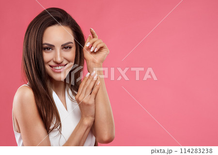 Beautiful young woman with clean perfect skin. Portrait of beauty model with natural nude make up and touching her face. Spa, skincare and wellness. Close up, copyspace. 114283238