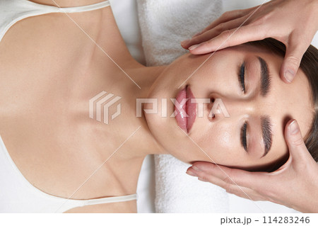 Face massage. Beautiful of young woman getting spa massage treatment at beauty spa salon.Spa skin and body care. Facial beauty treatment.Cosmetology. Face massage. Beautiful of young woman getting spa massage treatment at beauty spa salon.Spa skin and body care. Facial beauty treatment.Cosmetology. 114283246