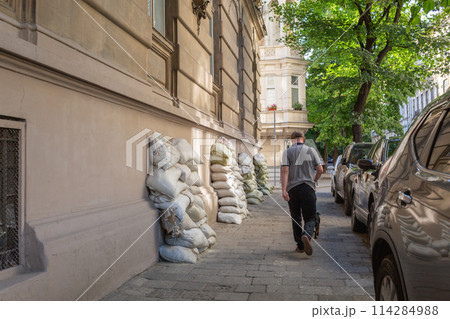 【ウクライナ】リヴィウ旧市街の土嚢が積み上げられた歩道を歩く男性の後ろ姿 114284988