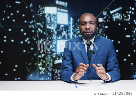 Anchorman working on live broadcast to discuss about latest events during night show segment, covering important topics. African american news reporter creating newscast with headlines. Anchorman working on live broadcast to discuss about latest events during night show segment, covering important topics. African american news reporter creating newscast with headlines. 114285059