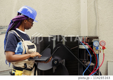 Licensed efficient electrician commissioned for leaks checking, making sure all hvac system vents are clear of waste. Precise serviceman doing air conditioner inspection, imputing data on laptop Licensed efficient electrician commissioned for leaks checking, making sure all hvac system vents are clear of waste. Precise serviceman doing air conditioner inspection, imputing data on laptop 114285163