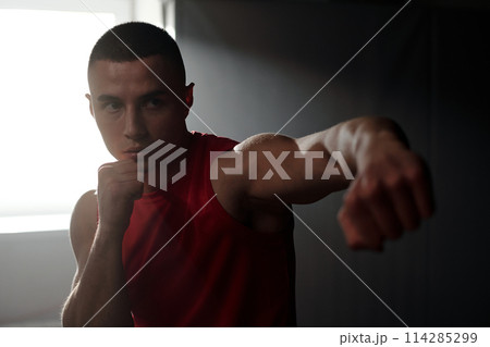 Guy with clenched fists practicing kicks Guy with clenched fists practicing kicks 114285299