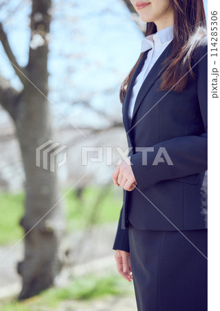 桜並木を歩くスーツを着た女性 114285306