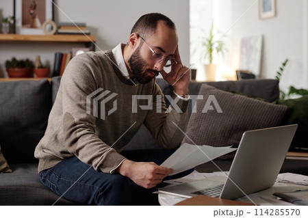Pensive man checking financial data Pensive man checking financial data 114285570