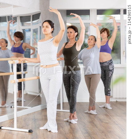 Group of women stand in third position at barre 114290515