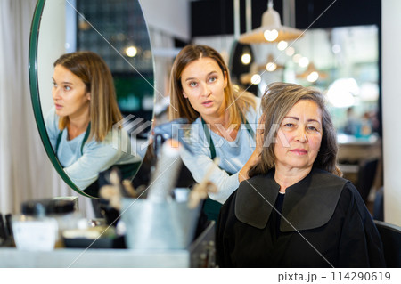 Elderly woman discussing hairstyling with professional hairdresser Elderly woman discussing hairstyling with professional hairdresser 114290619