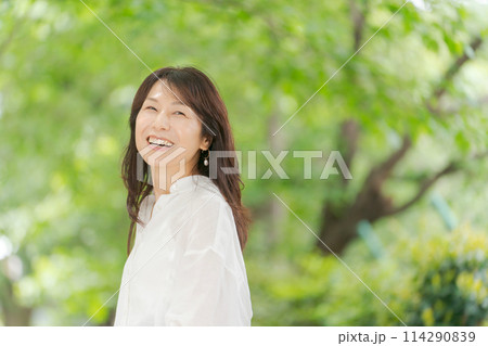 自然の中で微笑む白いシャツのミドル女性 114290839