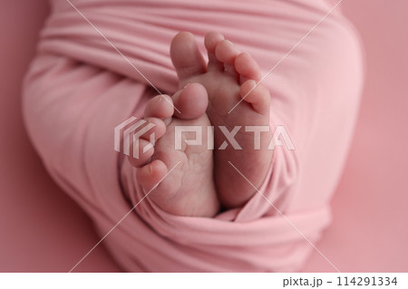 Close-up of tiny, cute, bare toes, heels and feet of a newborn girl, boy. Baby foot on pink soft coverlet, blanket. Detail of a newborn baby legs. Macro horizontal professional studio photo.  114291334