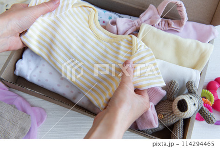 Women's hands collect children's clothes into boxes. Women's hands collect children's clothes into boxes. 114294465