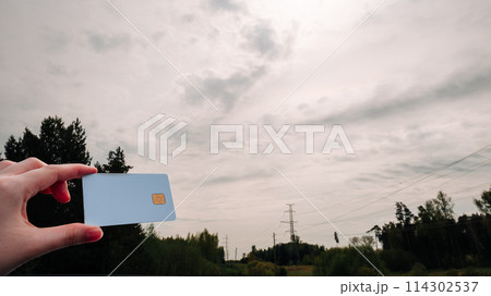 A person is holding a credit card in front of a cloudy sky A person is holding a credit card in front of a cloudy sky 114302537