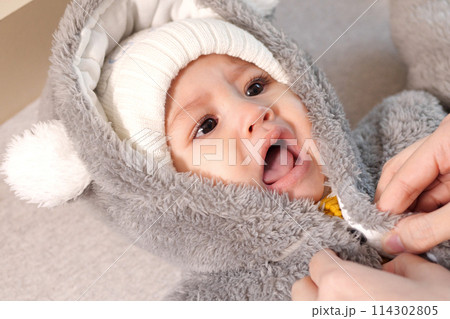 A mother dressing her little baby boy boy at home. childhood parenthood and growing up family concept real people 114302805