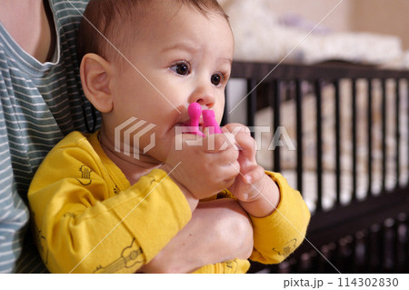 Cute adorable newborn baby playing with colorful rattle toy. baby with teether. six months old lovely baby portrait on white with teether toy 114302830