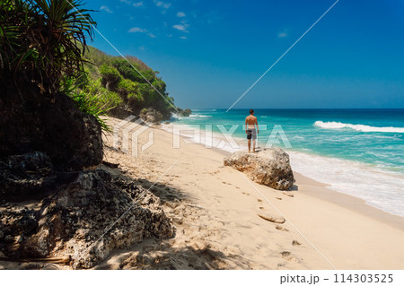 Guy shirtless on beach, summertime. Men staying on rock at ocean coastline. Guy shirtless on beach, summertime. Men staying on rock at ocean coastline. 114303525