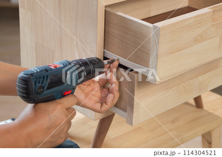 Handyman fixing over tight drawer slides rail of bedside table. Handyman fixing over tight drawer slides rail of bedside table. 114304521