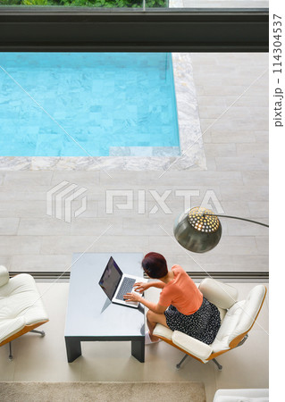 Senior digital nomad woman working at luxury villa in Phuket. andaman sea as background. Senior digital nomad woman working at luxury villa in Phuket. andaman sea as background. 114304537