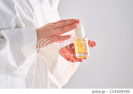 Blue serum with pipette in a womans hands in a robe. 114309390