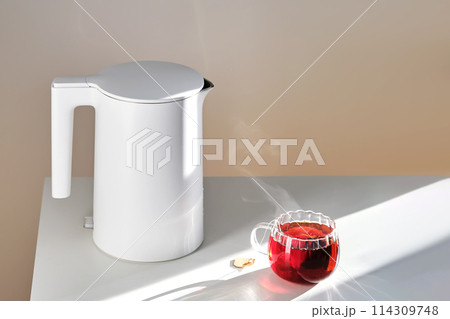 Glass mug with hot black tea on the table. 114309748