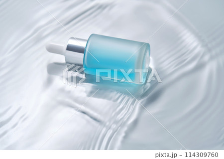 Bottles of cosmetics with a dropper in water on a blue background. Bottles of cosmetics with a dropper in water on a blue background. 114309760