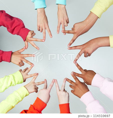 Close up of children's hands showing peace sign and standing in circle against grey background. Gestures. Close up of children's hands showing peace sign and standing in circle against grey background. Gestures. 114310697