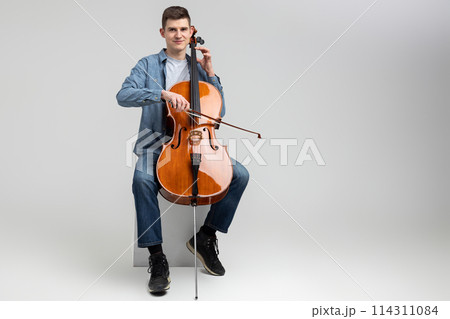 Attractive man musician playing cello on concert Attractive man musician playing cello on concert 114311084