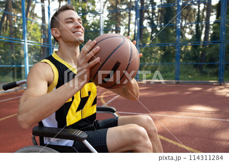 Handsome man with disability playing basketball in wheelchair Handsome man with disability playing basketball in wheelchair 114311284