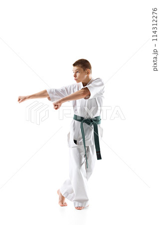 Focused martial arts student in white kimono and green belt prepares for fight, practicing isolated on white studio background 114312276