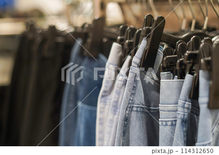Row of jeans on the hanger in the shop, selective focus. Concept of buy, sale and denim fashion 114312650