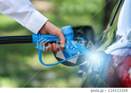 Man holds a hydrogen fueling nozzle. Refueling car with hydrogen fuel. Concept. Man holds a hydrogen fueling nozzle. Refueling car with hydrogen fuel. Concept. 114313104
