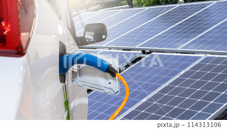 Close up of electric car with a connected charging cable on the background of solar panels.. Close up of electric car with a connected charging cable on the background of solar panels.. 114313106