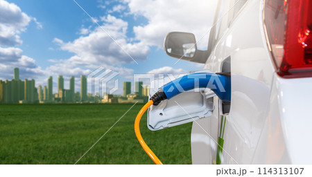 Close up of electric car with a connected charging cable on the background of green eco city 114313107