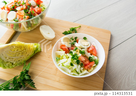 fresh vegetable salad, cabbage, tomatoes in a bowl on a wooden table fresh vegetable salad, cabbage, tomatoes in a bowl on a wooden table 114313531