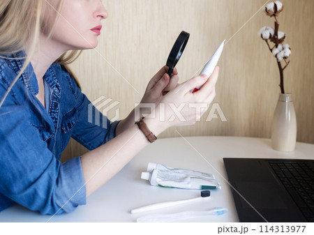 Toothpaste ingredients. Girl at laptop checks composition of toothpaste and is surprised by dangerous composition of product. Emulsifiers, preservatives, dyes, PEG, SLS, parabens, diethanolamine Toothpaste ingredients. Girl at laptop checks composition of toothpaste and is surprised by dangerous composition of product. Emulsifiers, preservatives, dyes, PEG, SLS, parabens, diethanolamine 114313977