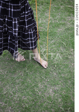 芝生の上で縄跳びをする裸足の女の子 114315054