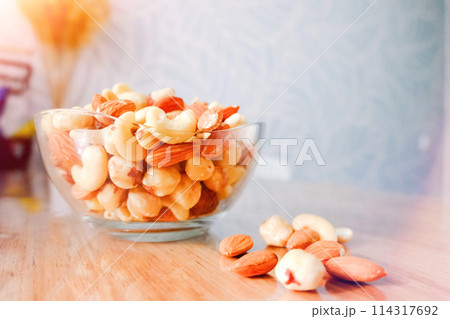 Cashews, peanuts and almonds on a plate. Nuts on the table in the bright rays of the sun. Cashews, peanuts and almonds on a plate. Nuts on the table in the bright rays of the sun. 114317692