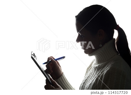 Young woman thoughtfully writes, draws, writes 114317720