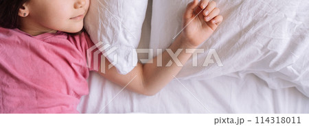 Little girl in pink pajamas sleeps in white bed linen Little girl in pink pajamas sleeps in white bed linen 114318011
