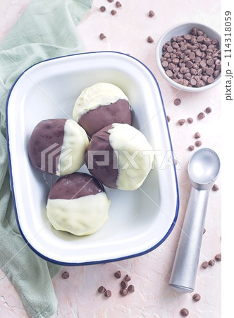 Dark and white chocolate covered ice cream sandwiches, on white plate, vertical, top view 114318059