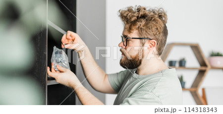 Banner bearded millennial man assemble his bookcase. He uses tools for furniture copy space. Furniture for the interior room or apartments 114318343