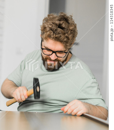 Young attractive man assembles furniture - handwerker and interior objects concept Young attractive man assembles furniture - handwerker and interior objects concept 114318345