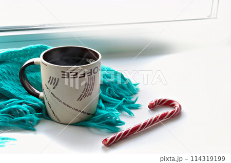 A mug of hot coffee is on the windowsill. 114319199