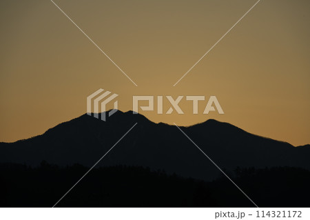 朝の光が空を黄金色に染め茅ヶ岳の鞍部から昇る太陽 114321172
