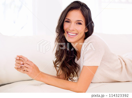 Portrait, happy or woman on couch to relax in living room on holiday in hotel, house or apartment. Lying down, sofa or female person with smile, wellness or confidence on break to rest in alone time 114323392
