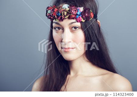 Woman, portrait and flower headband in hair with beauty, skin glow and wellness on grey background. Face, hairstyle with floral head gear or accessory, dermatology and cosmetics to blossom in studio 114323400