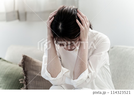 リビングで頭を抱える女性　頭痛　体調不良 114323521