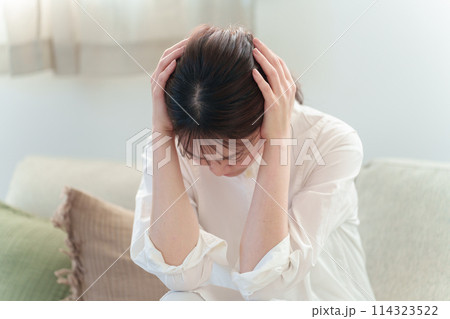 リビングで頭を抱える女性　頭痛　体調不良 114323522