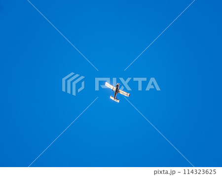 Small ultralight airplane with overhead wing and single propeller flying in sunset sky. 114323625