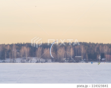 Kite surfer ride on snowboard. Snowkiting in the snow on frozen lake. 114323641