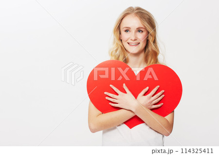Young woman, red heart or happiness in studio for wellness, love or romantic review on valentines day. American model, positive and smile with care symbol for support and opinion by white background Young woman, red heart or happiness in studio for wellness, love or romantic review on valentines day. American model, positive and smile with care symbol for support and opinion by white background 114325411